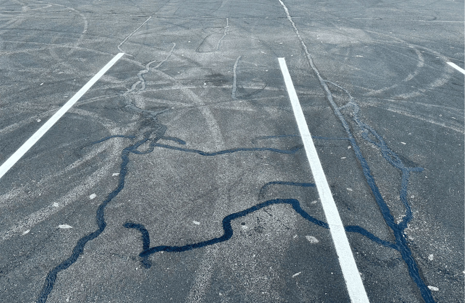 Asphalt Parking Lot with Crack Filling Applied Close-up view of an asphalt parking lot with crack filling applied to repair surface cracks