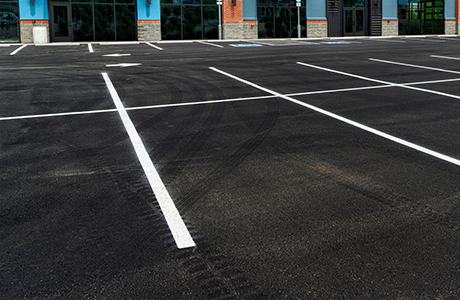 Freshly paved commercial parking lot with clear white line striping in front of a business building