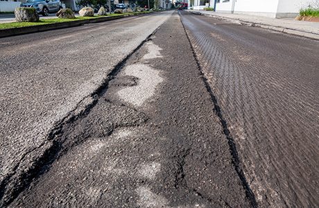 Close-up of a road undergoing asphalt milling services, with visible grooves and removed layers of the old asphalt surface