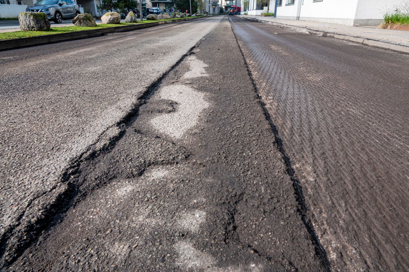 Road Milling Services for Asphalt Pavement Repair Close-up of a road undergoing asphalt milling services, with visible grooves and removed layers of the old asphalt surface