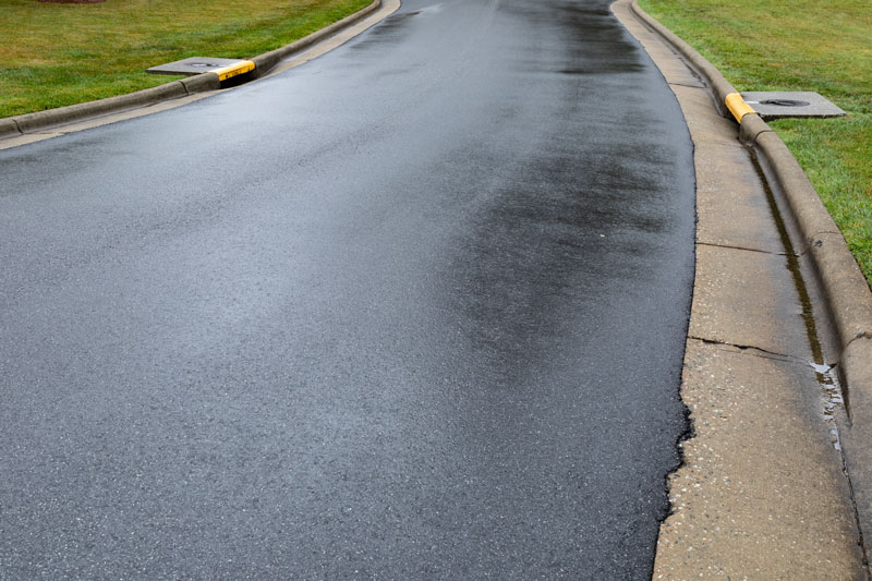 Newly Paved Road After Asphalt Milling to Improve Drainage Freshly paved road after asphalt milling to improve drainage, with smooth surface and visible curbside drainage systems
